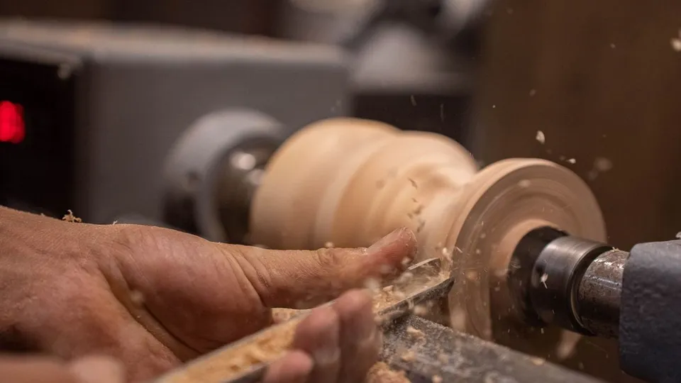 Mains qui tournent une pièce de bois sur un tour d'artisan
