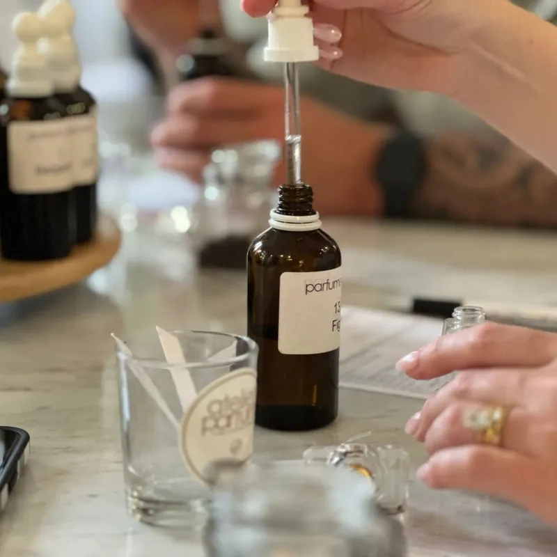Mains qui dosent une essence lors d'un atelier de parfumerie