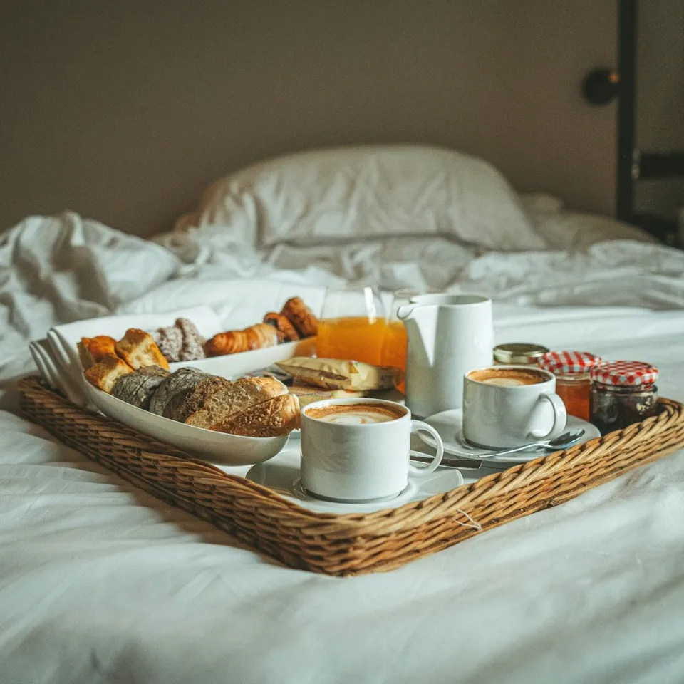 Plateau de petit-déjeuner servi sur un lit en lin blanc