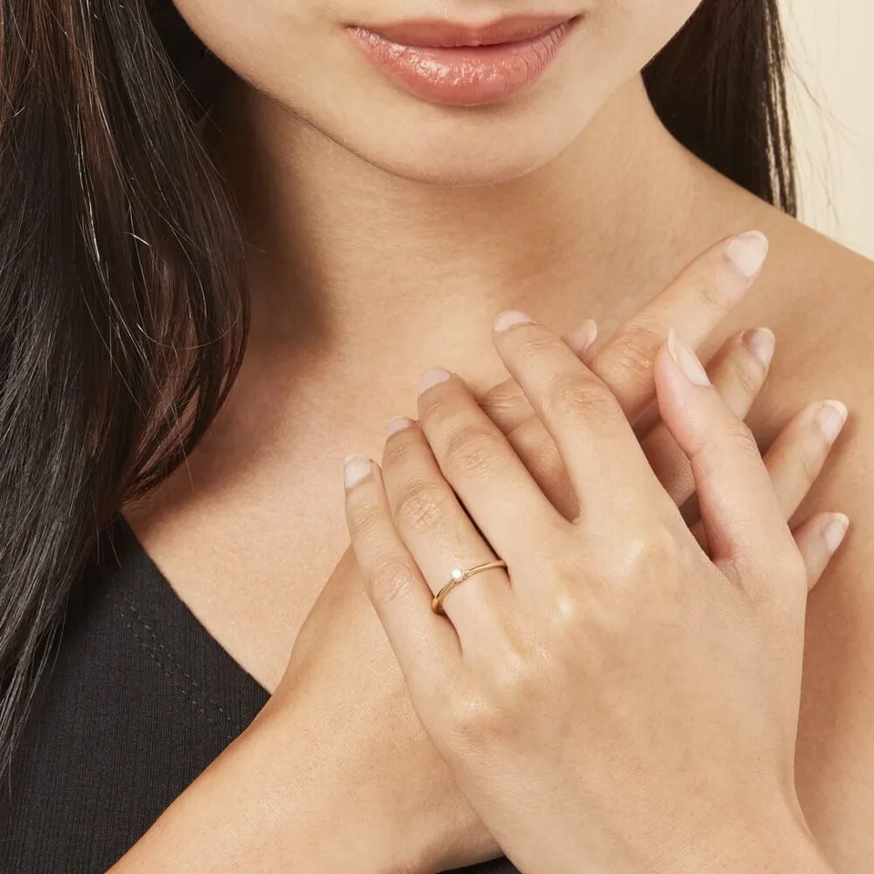 Bague solitaire en or portée, mains croisées