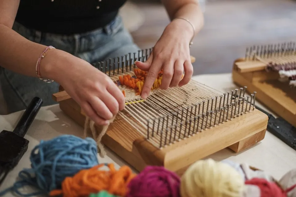Mains qui tissent la laine sur un petit métier