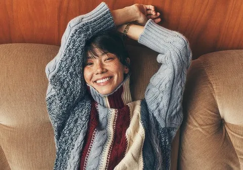 Femme souriante enveloppée dans un gilet en maille