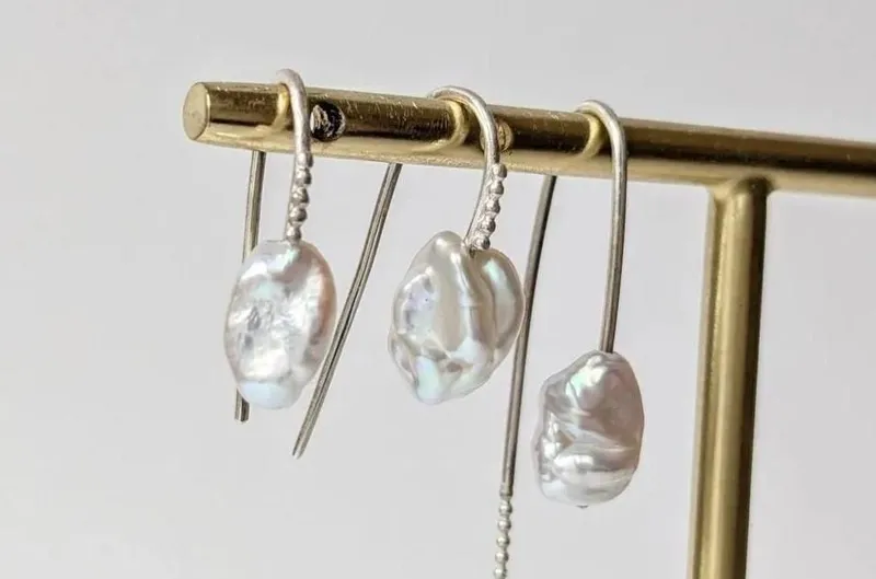 Boucles d'oreilles en perles baroques sur un présentoir doré