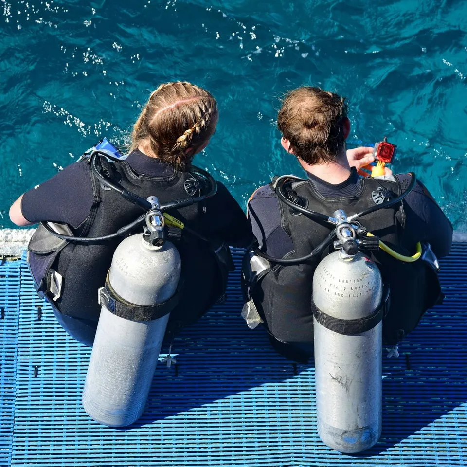 Deux plongeurs équipés au bord d'une eau turquoise